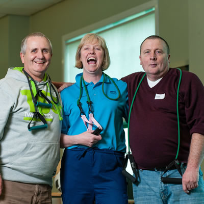 Female therapist laughing with 2 male members of the pulmonary rehabilitation class