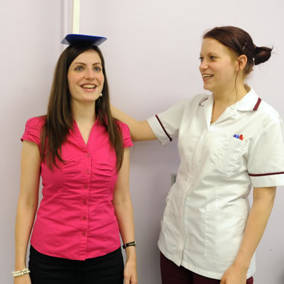 Female patient having height taken by a female nurse