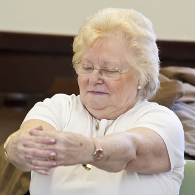 A woman stretching her arms out in front of her with her eyes closed
