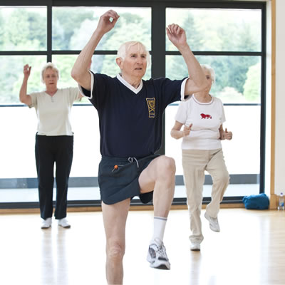 An aerobic exercise class for senior mature men and women, led by an instructor.