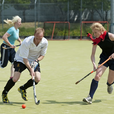 A group of men and women playing hockey